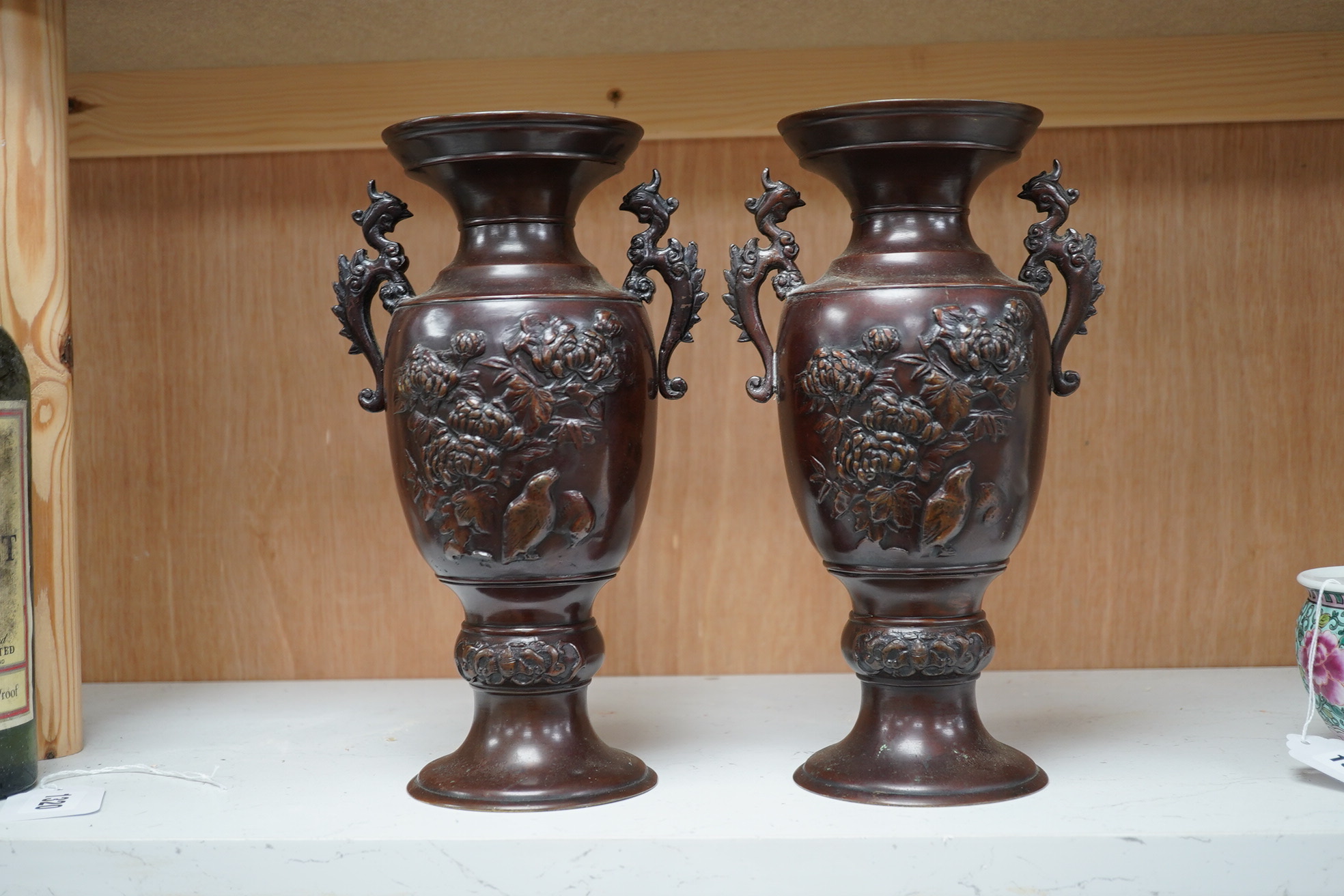 A pair of Japanese two handled bronze vases decorated in relief with birds and flowers, 26cm high. Condition - good